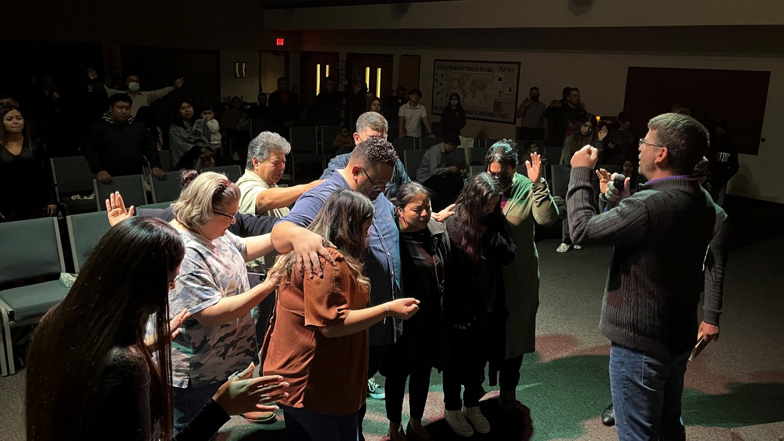 Miembros de la iglesia orando unos por otros durante un servicio